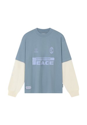 Koszula z długim rękawem w kolorach niebieskim i kremowym z napisem "PEACE" oraz małymi logo na piersi i naszywką przy dolnym brzegu.