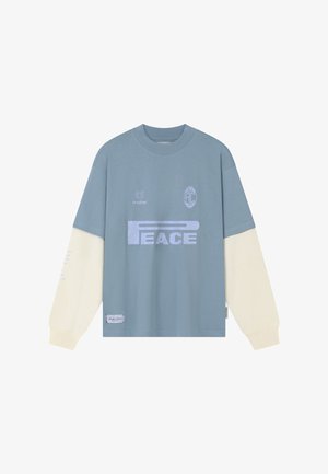 Hosszú ujjú, kék és krémszínű színblokkolt ing "PEACE" felirattal, kis logókkal a mellkason és egy folttal az alja közelében.