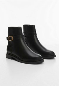 Zwarte leren enkellaarzen met een gladde textuur, een ronde neus en een gouden gespaccent op de riem rond de enkel. Platte zool.