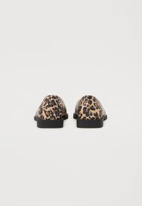 Mocasines con estampado de leopardo, con un acabado de cuero suave, suelas de goma negra y diseño de punta redonda, que muestran un patrón animal distintivo.