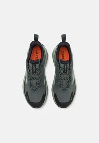 Pantofii sport gri și negri au o parte superioară texturată, accente reflectorizante și un guler cu umplutură, cu detalii verzi și tălpi portocalii.