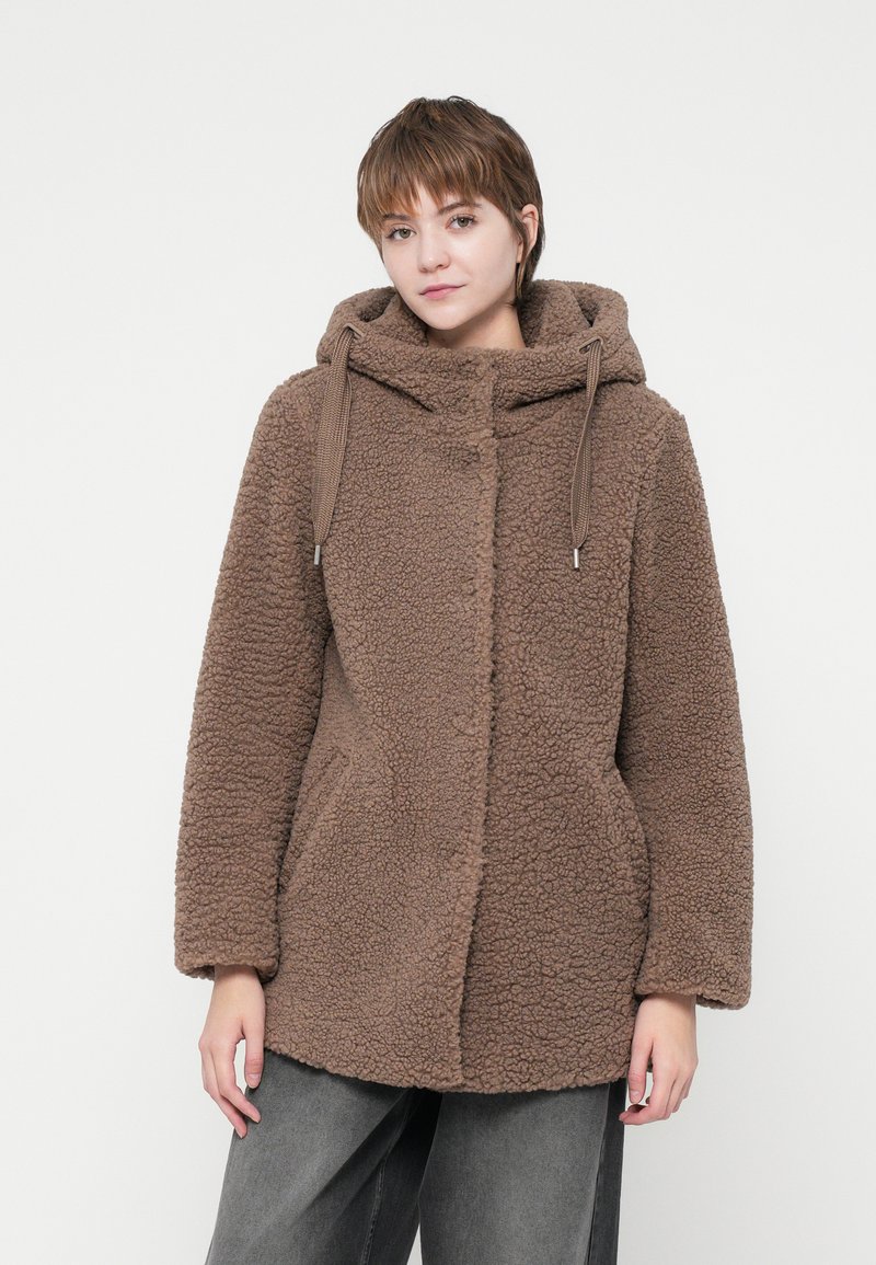 Hnedý fleece kabát s kapucňou, textúrovaný povrch, predné zapínanie na gombíky a bočné vrecká, nosený cez tmavošedé nohavice.