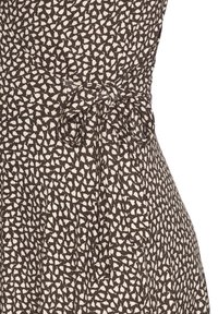 Braun und weiß abstrakt gemusterte Kleid mit einem gebundenen Stoffgürtel in der Taille, der die gerafften Falten unterhalb des Gürtels betont.