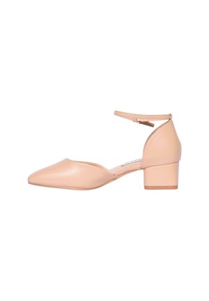 Scarpa con cinturino alla caviglia in pelle beige, con punta affusolata e tacco a blocco di media altezza, caratterizzata da una superficie liscia e un design minimalista.