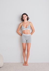 Gray cotton bralette with thin straps and matching boyshorts, featuring a white elastic band with the brand name. Simple, comfortable design.