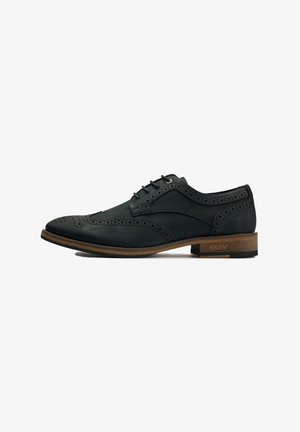 Black leather dress shoe with brogue detailing, lace-up design, rounded toe, and a light brown wooden heel. Subtle texture throughout.