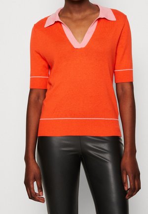 Oranje gebreide top met een roze kraag, korte mouwen en een diepe V-hals. Heeft witte accentlijnen bij de mouwen en de zoom. Soepele textuur.