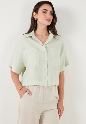 Lichtgroen kortemouw blouse met twee voorzakken, kraagontwerp en een losse pasvorm, gemaakt van een zachte, gestructureerde stof.