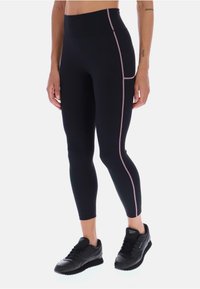 Černé legíny s vysokým pasem mají růžové kontrastní švy a boční kapsu. Materiál vypadá hladce a elasticky.