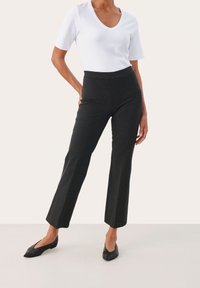 Pantalon gris ajusté avec une coupe droite, fabriqué en matière lisse. Associé à un T-shirt blanc à col en V et des ballerines noires à bouts pointus.