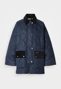 Tengerészkék steppelt dzseki kordbársony gallérral, két fekete kordbársony zsebbel, arany kiegészítőkkel, és egy arany logóval a bal zsebnél.