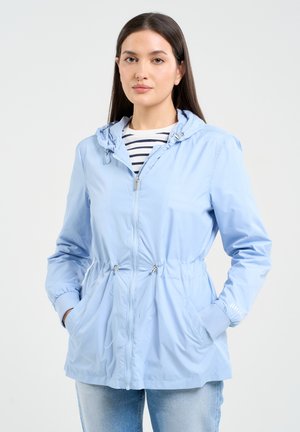 Jasnoniebieska wodoodporna kurtka z kapturem, elastycznymi mankietami, regulowanym pasem i dwiema przednimi kieszeniami. Pod spodem pasiasty T-shirt.