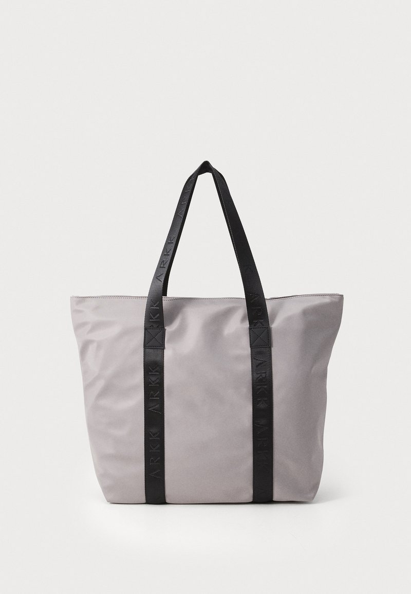 Sac fourre-tout gris avec des anses noires à logo, dotée d'une texture douce et d'un design à ouverture haute. Forme simple et rectangulaire avec un minimum de détails.
