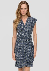 Marineblauwe wikkeljurk met korte capmouwen, voorzien van een geometrisch bloemenpatroon en een strik in de taille, gemaakt van lichte stof.