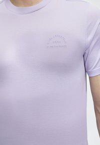 Ανοιχτό μωβ κοντομάνικη μπλούζα με μικρό ανάγλυφο κείμενο "KARL LAGERFELD PARIS 21 RUE ST-GUILLAUME" στο αριστερό στήθος.