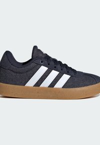 Dark navy canvas sneakers with white side stripes, textured upper, and a gum rubber sole with speckles. Laced design with a padded collar.