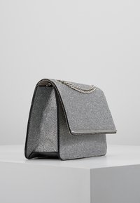 Borsa handbag testurizzata argento con pattina pieghevole, tracolla a catena e rifinitura nera liscia. Forma rettangolare compatta con una finitura lucente.