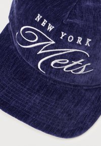 Boné em veludo cotelê azul-marinho com bordado "NEW YORK" e logotipo em caligrafia "Mets" em branco. A pala se projeta para frente com um acabamento texturizado.