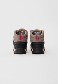 Pair of brown and black hiking boots with red pull tabs viewed from the back against a white background.