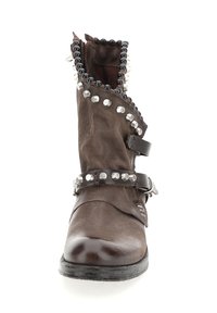 Brown leather ankle boot with a slouched design, silver and black stud accents, a side zipper, and a chunky sole.