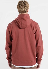 Sweat à capuche couleur rouille avec capuche à cordon de serrage, arborant un détail logo sur l'épaule gauche et des poignets et un ourlet côtelés pour un ajustement confortable.