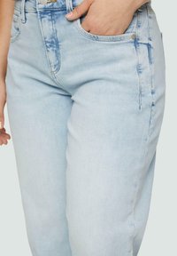 Jean en denim bleu clair avec une coupe droite. Les caractéristiques incluent une poche frontale, des zones légèrement décolorées et des détails de couture visibles.