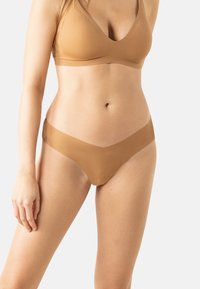 Soutien-gorge seamless couleur peau et string assorti, avec une texture lisse en relief, un décolleté en V et une coupe minimaliste pour le confort et le style.