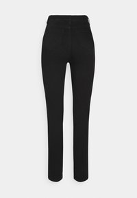 Jean noir taille haute slim-fit avec poches arrière, jambes droites et coutures visibles, présenté sur fond blanc.