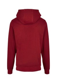 Czerwona bluza z kapturem o miękkiej teksturze, wyposażona w kieszeń typu kangur i ściągacze na rękawach. Kaptur ma bezszwowy design z tyłu.