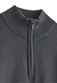 Pullover grigio a maglia con colletto alto e zip a un quarto. Presenta una texture a coste e un tessuto liscio. Hardware della cerniera in nero.