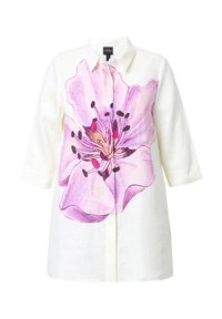 Chemise en lin blanc avec un grand imprimé floral rose sur le devant, style boutonné avec des manches trois-quarts.