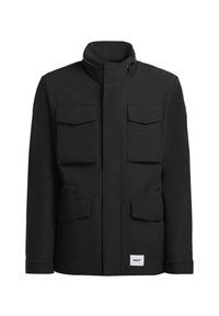 Veste noire homme avec quatre poches à rabat à l'avant, col montant et fermeture éclair frontale masquée par une large patte, étiquette de marque blanche rectangulaire en bas à droite.