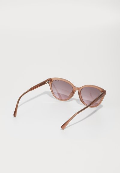 Ochelari de soare din plastic maro, cu lentile gradient violet, formă oversized în stil cat-eye și brațe elegante, curbate. Accentele includ o marcă subtilă pe ramă.