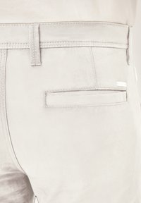 Helle graue Hose aus weichem Stoff mit glatter Textur. Verfügt über eine Gesäßtasche mit einem dezenten Stichdetail und einem Etikett.