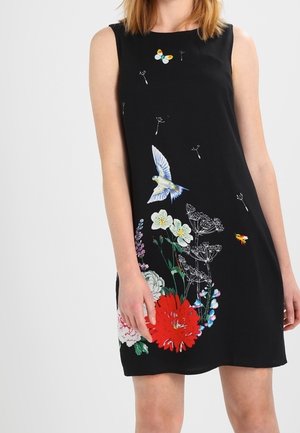 Mouwloze zwarte jurk met kleurrijke bloemen-, vogel-, vlinder- en bijenprints aan de voorkant, gedragen door een vrouw die staat.