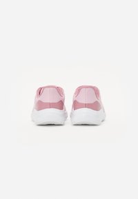 Par de zapatillas de running de malla rosa con suelas blancas mostradas desde atrás sobre un fondo blanco.