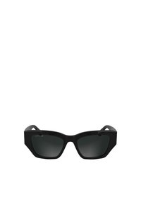 Lunettes de soleil noires avec une monture géométrique, verres teintés foncés et matériau plastique lisse. Présente un logo discret sur le côté.