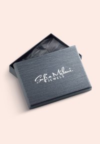 Grå smykkæske med en struktureret finish, let åben, med et hvidt logo: "Sofia Milani JEWELS," og sort silkepapir indeni.