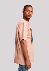 Helles rosa Baumwoll-T-Shirt mit kurzen Ärmeln, das einen bunten Grafikdruck auf der Vorderseite hat. Lässige Passform, Rundhalsausschnitt, weicher Stoff.
