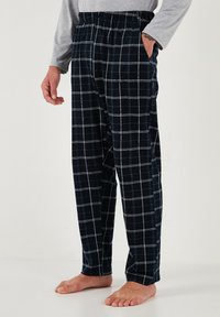 Pantalones de pijama a cuadros en color navy, fabricados con una tela suave, con cintura elástica, bolsillos laterales y patrones en cuadrícula blanca.