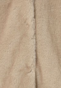 Tela de piel sintética beige con una textura suave y mullida, que presenta una superficie lisa y uniforme con un brillo sutil, ideal para prendas o accesorios.