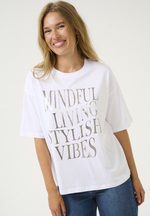 T-shirt blanc à manches courtes avec un texte métallique argenté "VIVRE EN CONSCIENCE, VIBES STYLÉES". Coupe décontractée et tissu doux, conçu pour le confort.