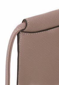 Bolso de mano de textura rosa con un suave borde negro, que muestra un sutil patrón de tejido y costuras detalladas a lo largo de los bordes.