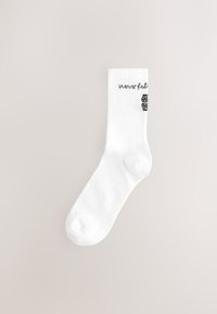 Chaussette blanche mi-mollet avec bord côtelé, arborant le texte noir « never fully » et un petit graphique noir de cerveau sur le côté.