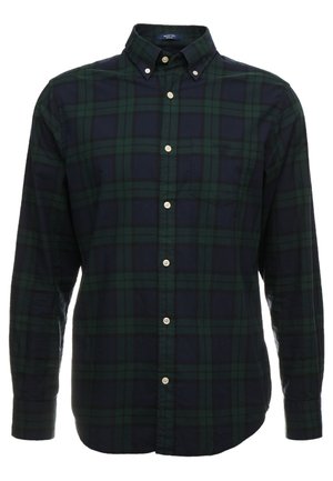 Chemise à manches longues en flanelle à carreaux verts foncés et bleu marine, avec col boutonné et boutons blancs.