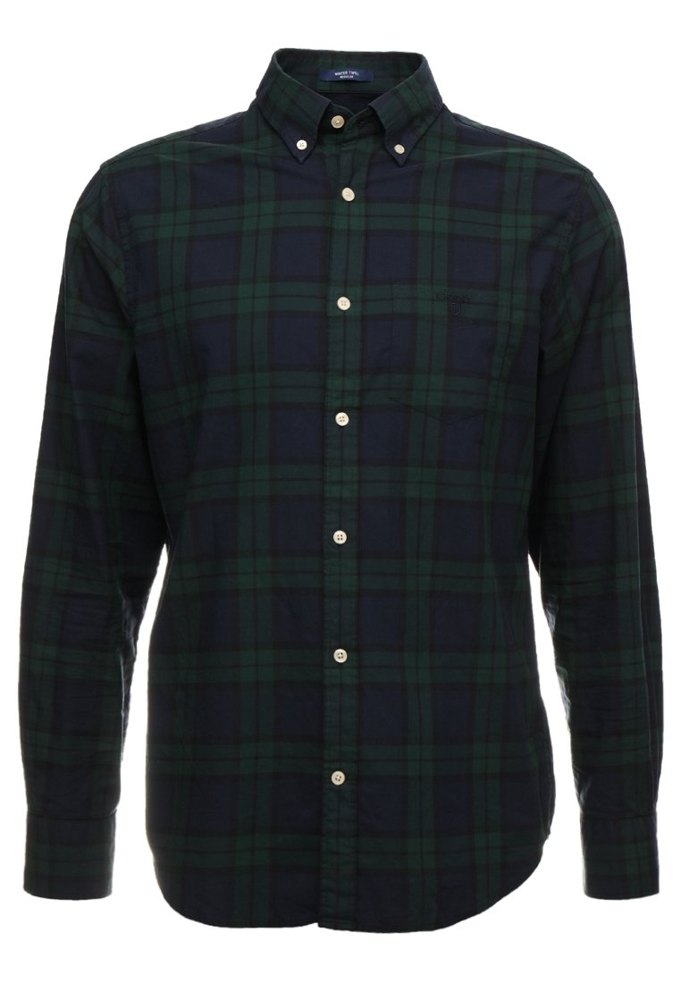 Chemise à manches longues en flanelle à carreaux verts foncés et bleu marine, avec col boutonné et boutons blancs.