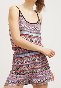 Flerfärgad leotard med ett geometriskt och tribal mönster, med en åtsittande midja, spagettiaxlar och ett lätt tyg.