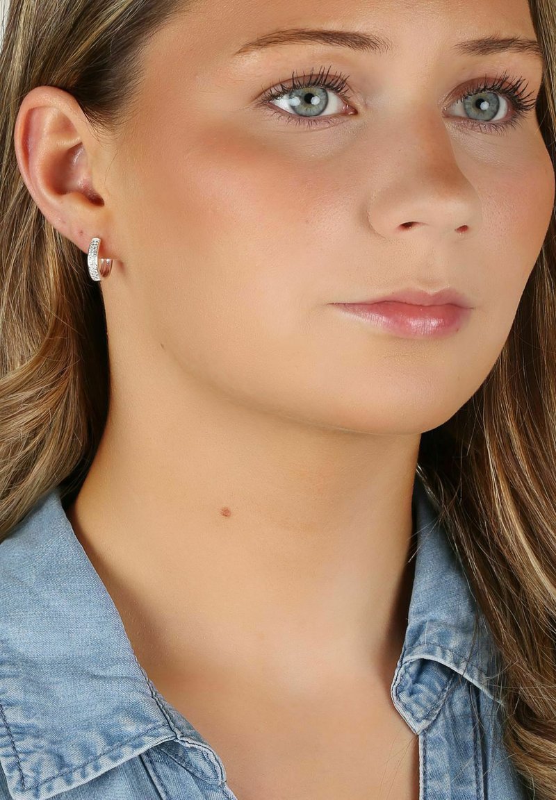 Silverfärgade hoops med en strukturerad yta som har små inbäddade stenar. Designen är elegant och minimalistisk, vilket gör dem lämpliga för vardagligt bruk.