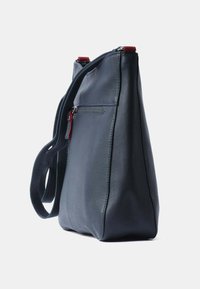 Marineblauwe leren handtas met een gestructureerde vorm, verstelbare schouderriem en rode ritssluiting. Inclusief externe ritsvak.