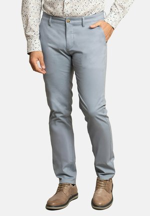 Pantalones gris claro de tela suave, con cierre de botón, bolsillos inclinados y corte slim, combinados con zapatos marrones.